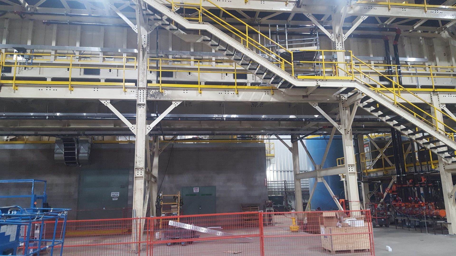 Industrial interior with a metal staircase and scaffolding painted yellow.