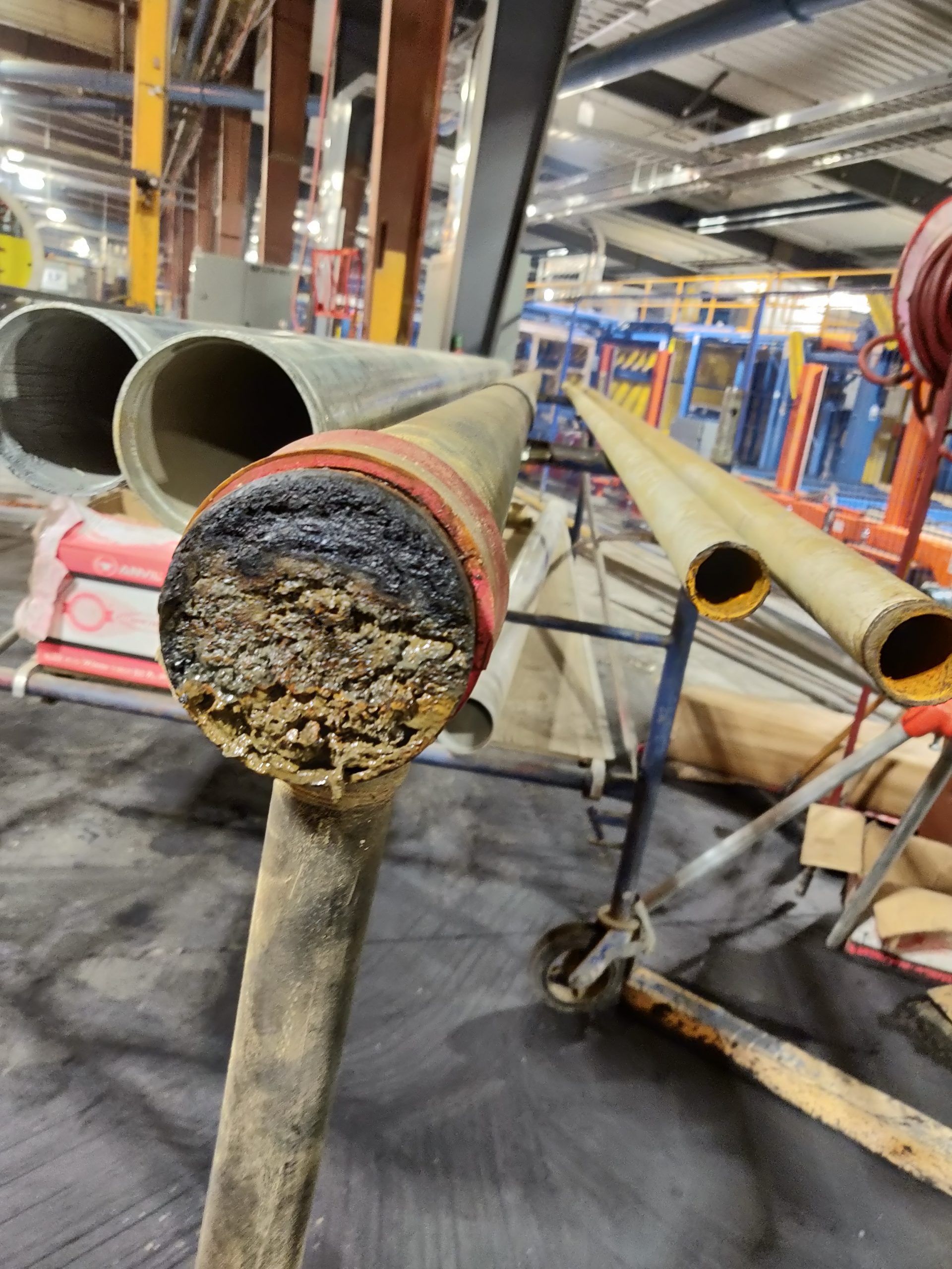 Close-up of a damaged, cut pipe with a charred end, possibly industrial setting.