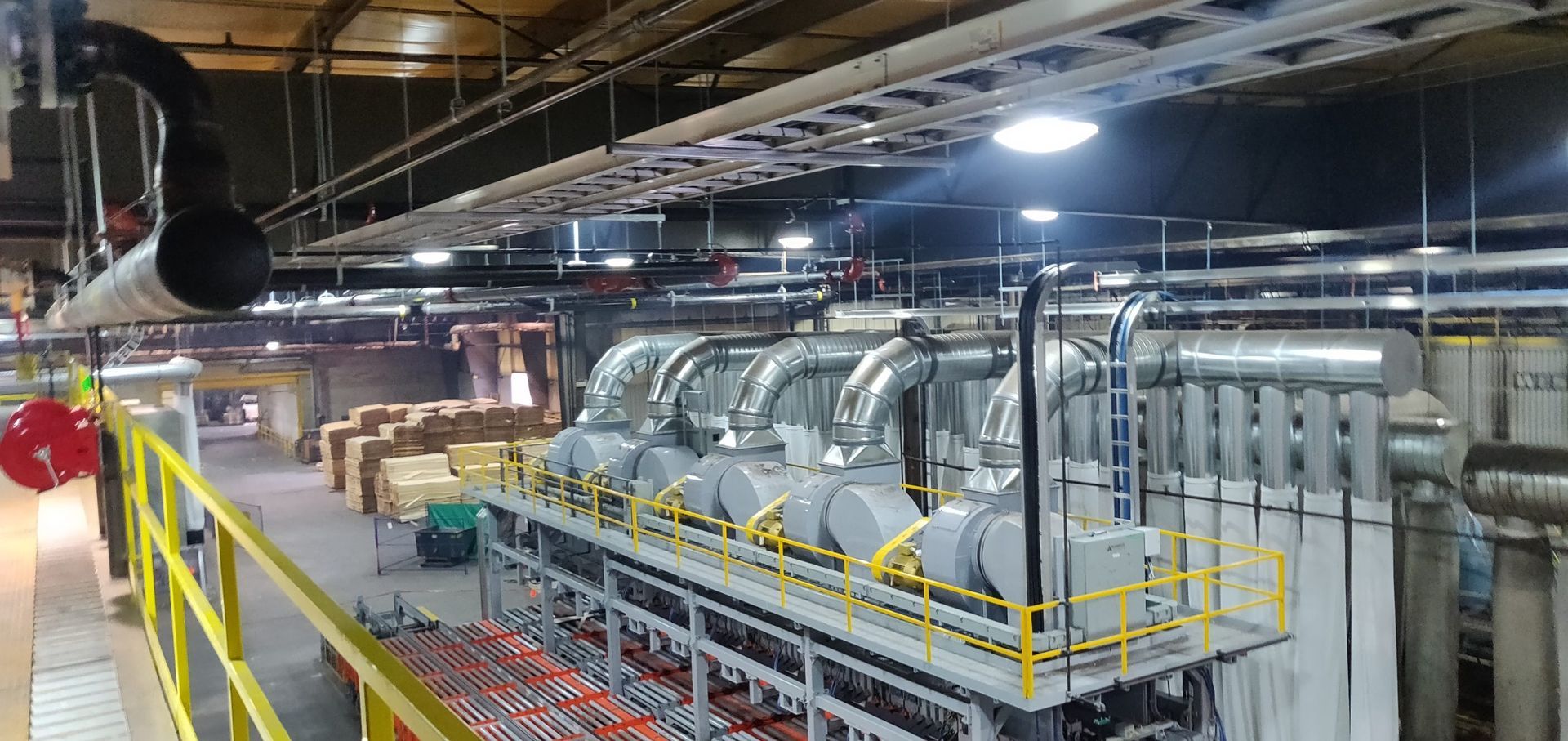 Interior of a factory floor with machinery, pipes, and walkways.