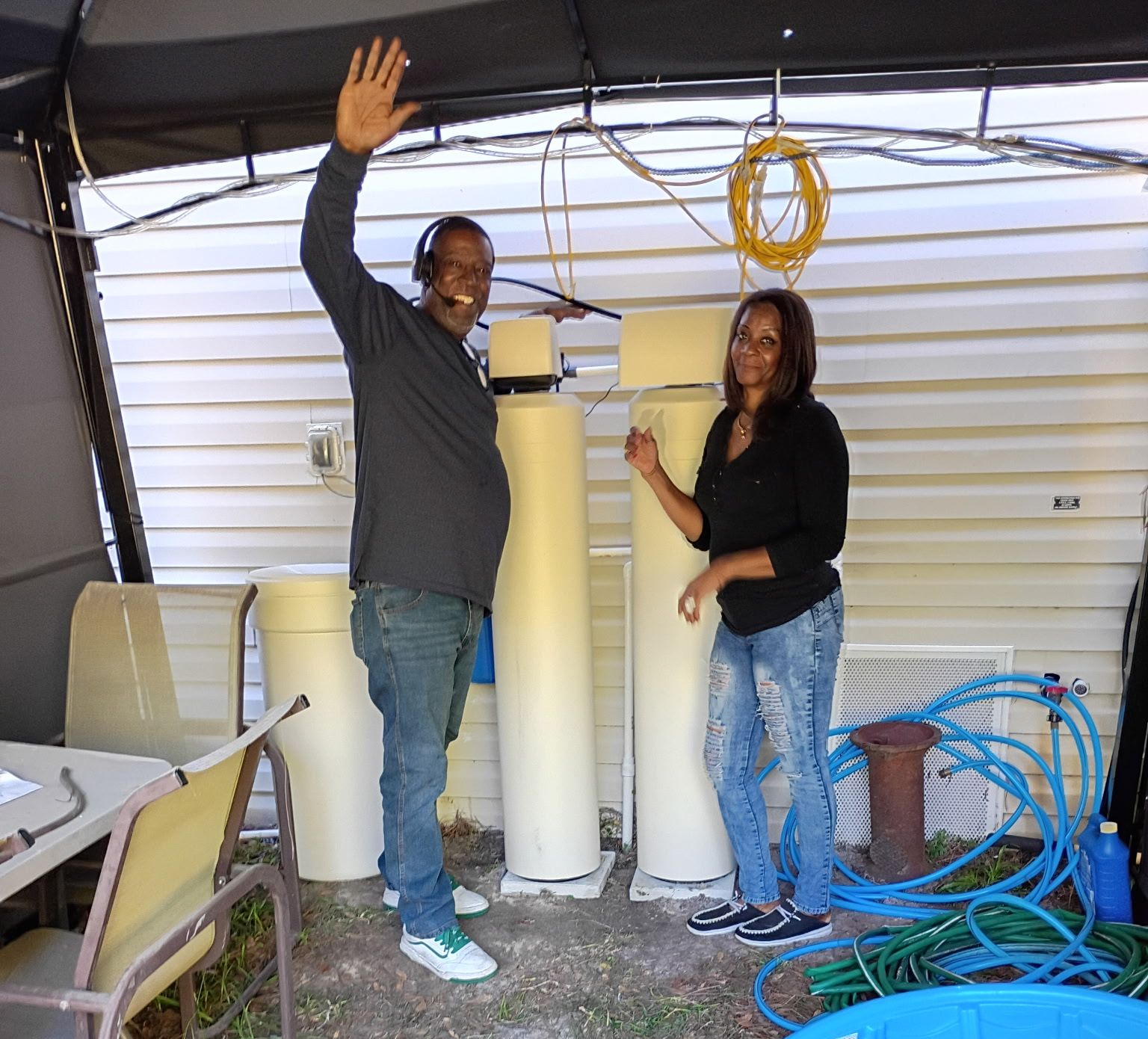 Man opening a small outdoor utility shed to inspect blue water equipment inside