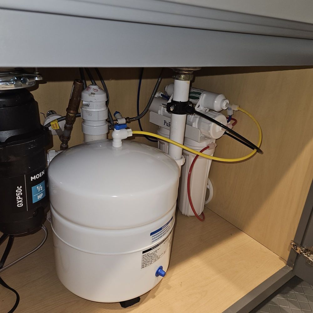Under-sink reverse osmosis water filtration system with tanks, pipes, and hoses in a cabinet