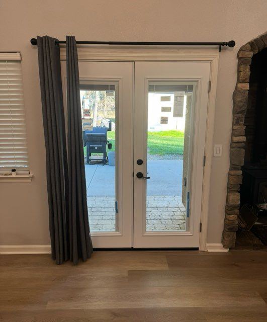 French doors with gray curtains in a living room, showing a driveway and yard outside.