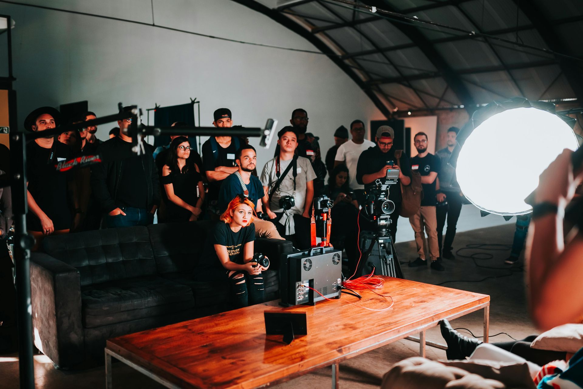 Equipo de rodaje en una gran sala, filmando. Varias personas observan a los actores. Una gran luz ilumina la escena.