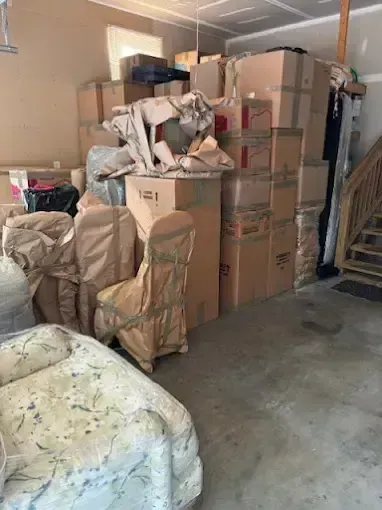 Mover wrapping furniture with protective plastic in a room with boxes and a ladder Mover wrapping furniture with protective plastic in a room with boxes and a ladder