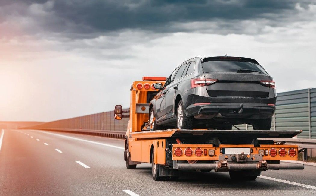 Black SUV on an orange car carrier driving on a highway Black SUV on an orange car carrier driving on a highway