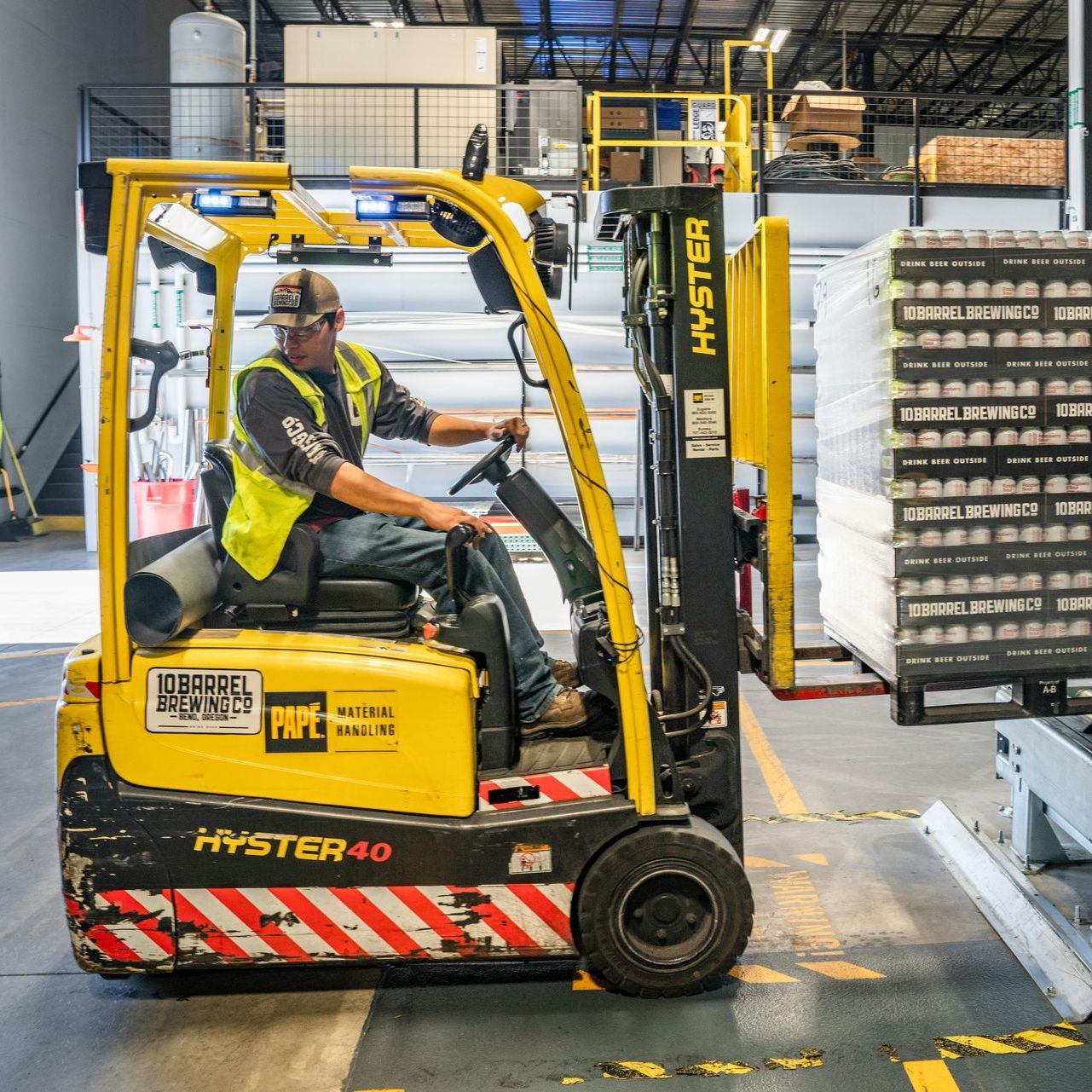 A man is driving a hyster forklift in a warehouse