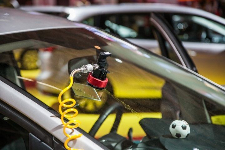 Mannequin in a car with a yellow coiled hose and mounted tool near the windshield