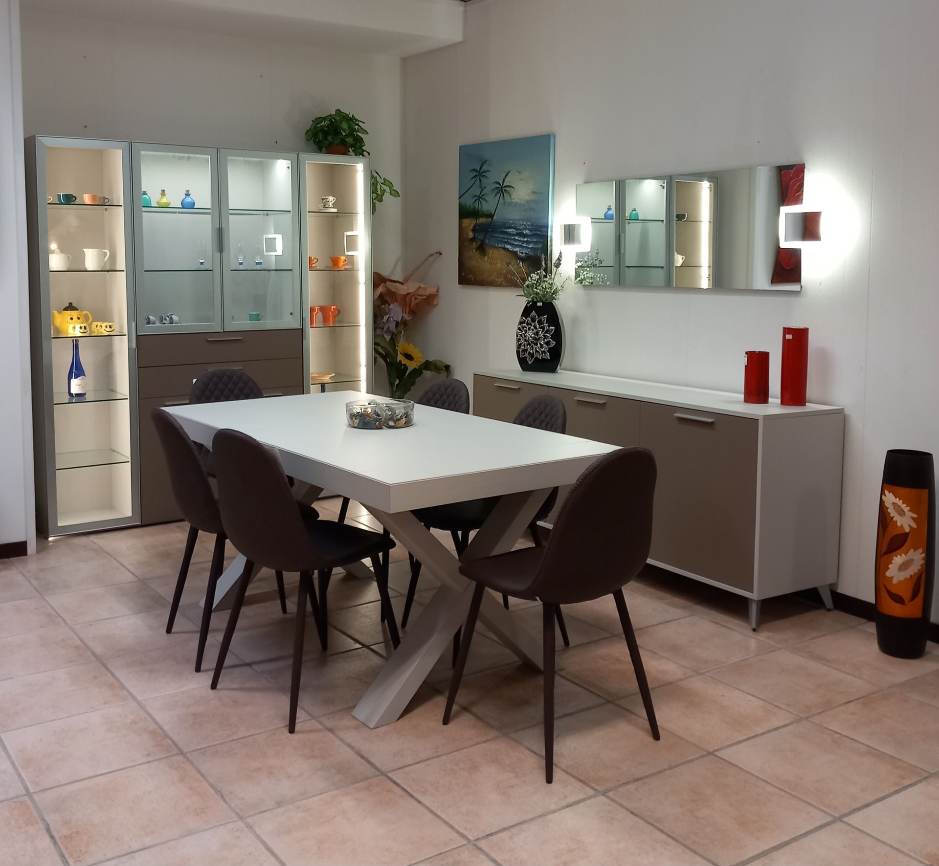 Sala da pranzo con tavolo bianco, sedie, mobili, quadri e una lampada da terra.