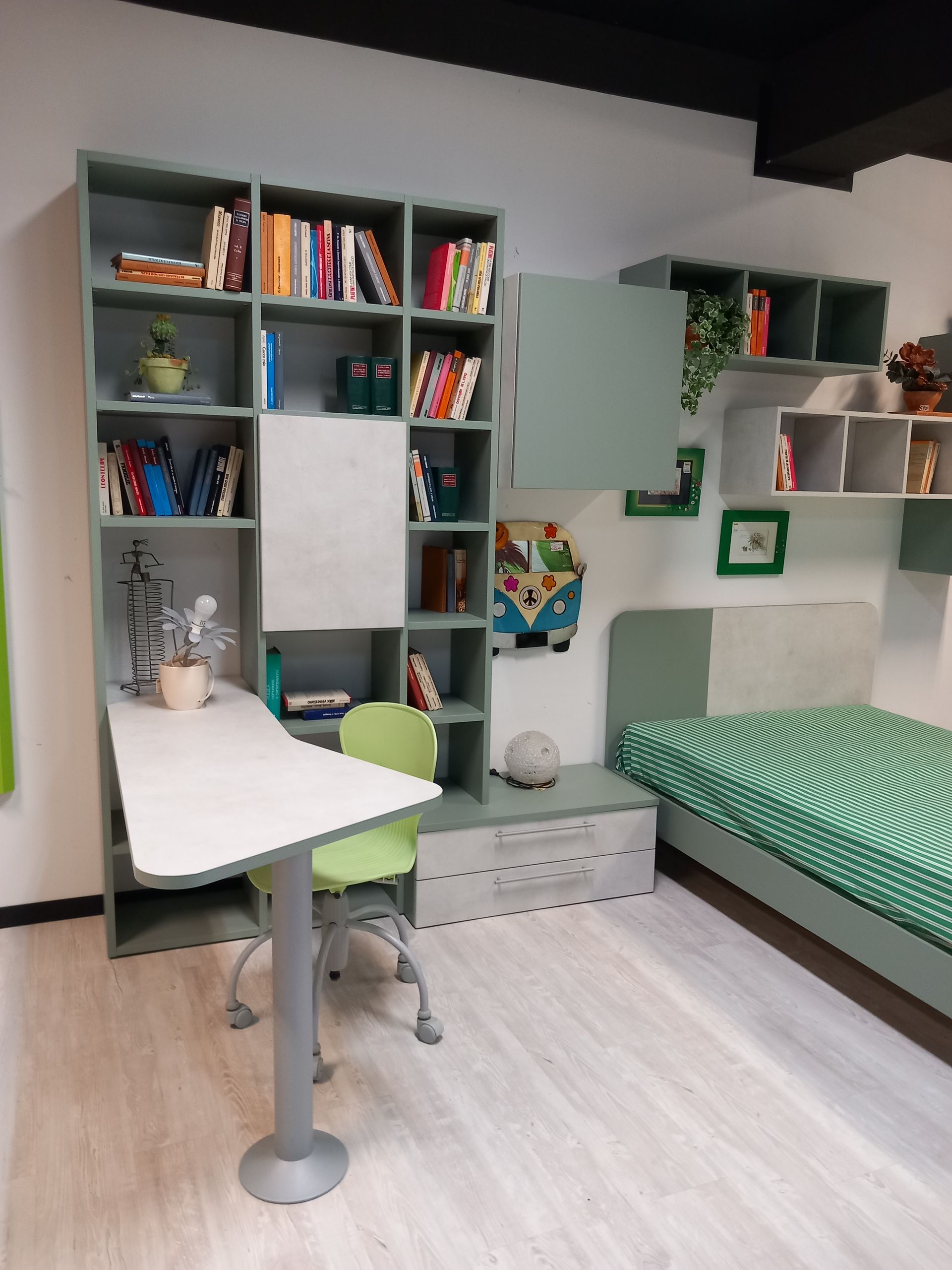 Una cameretta per bambini con mobili a tema verde, tra cui una scrivania, un letto e delle librerie.