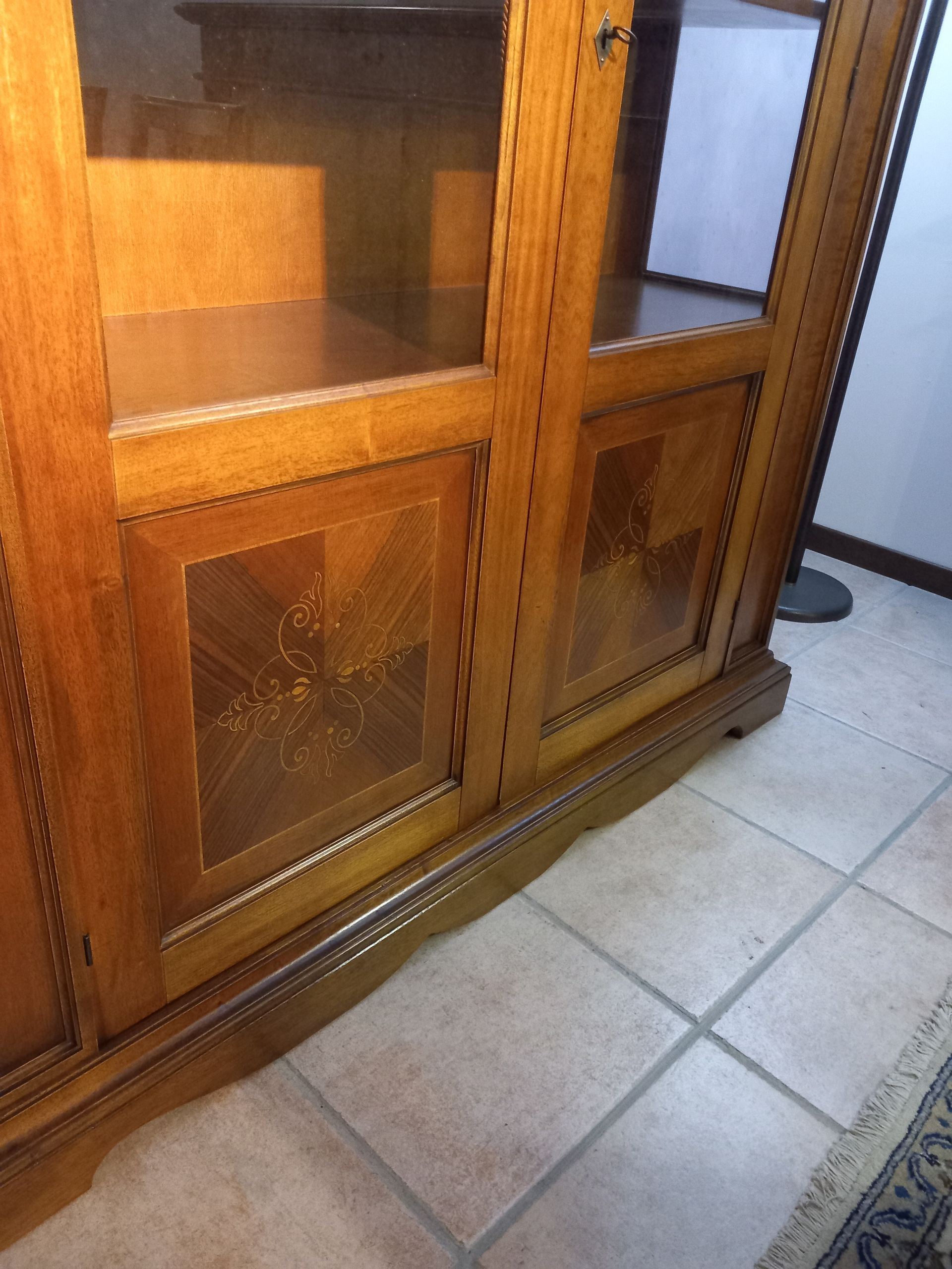 Vetrina portaoggetti in legno con ante in vetro e pannelli decorativi.