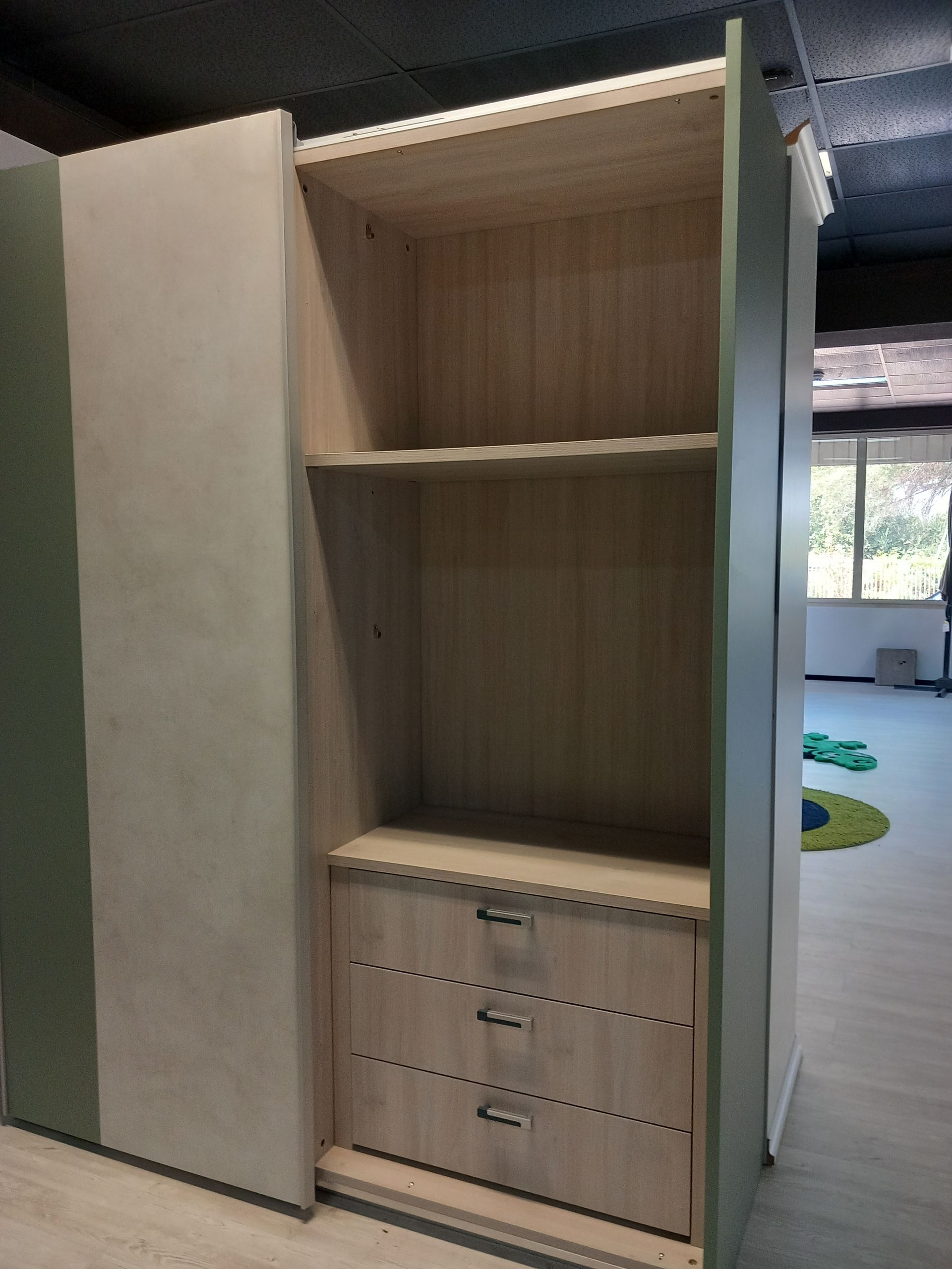 Mobiletto aperto in legno grezzo con ripiani e cassetti. Legno chiaro con finiture verdi.