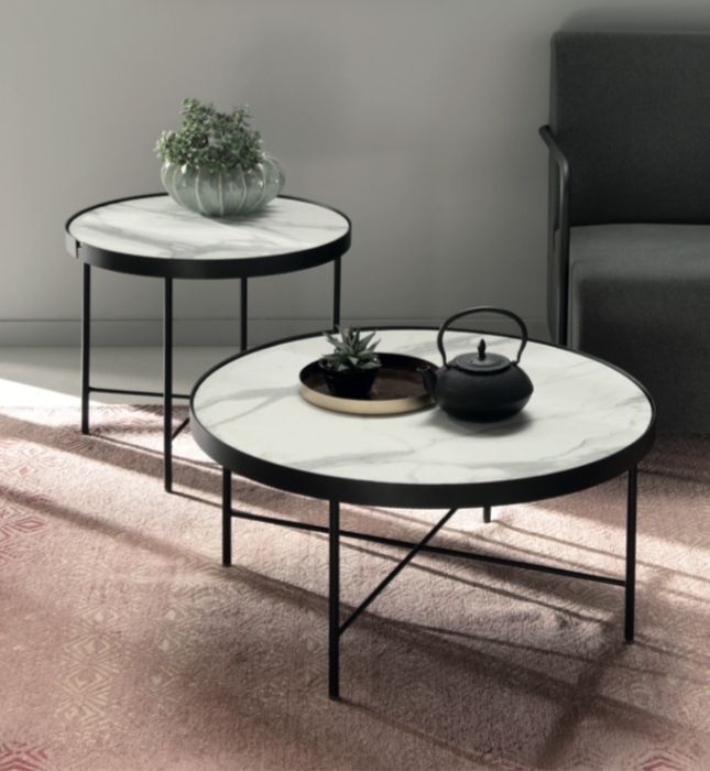 Due tavoli rotondi con piano in marmo e struttura in metallo nero. Uno contiene delle piante, l'altro un vassoio e una teiera; il tutto poggiato su un tappeto rosa.