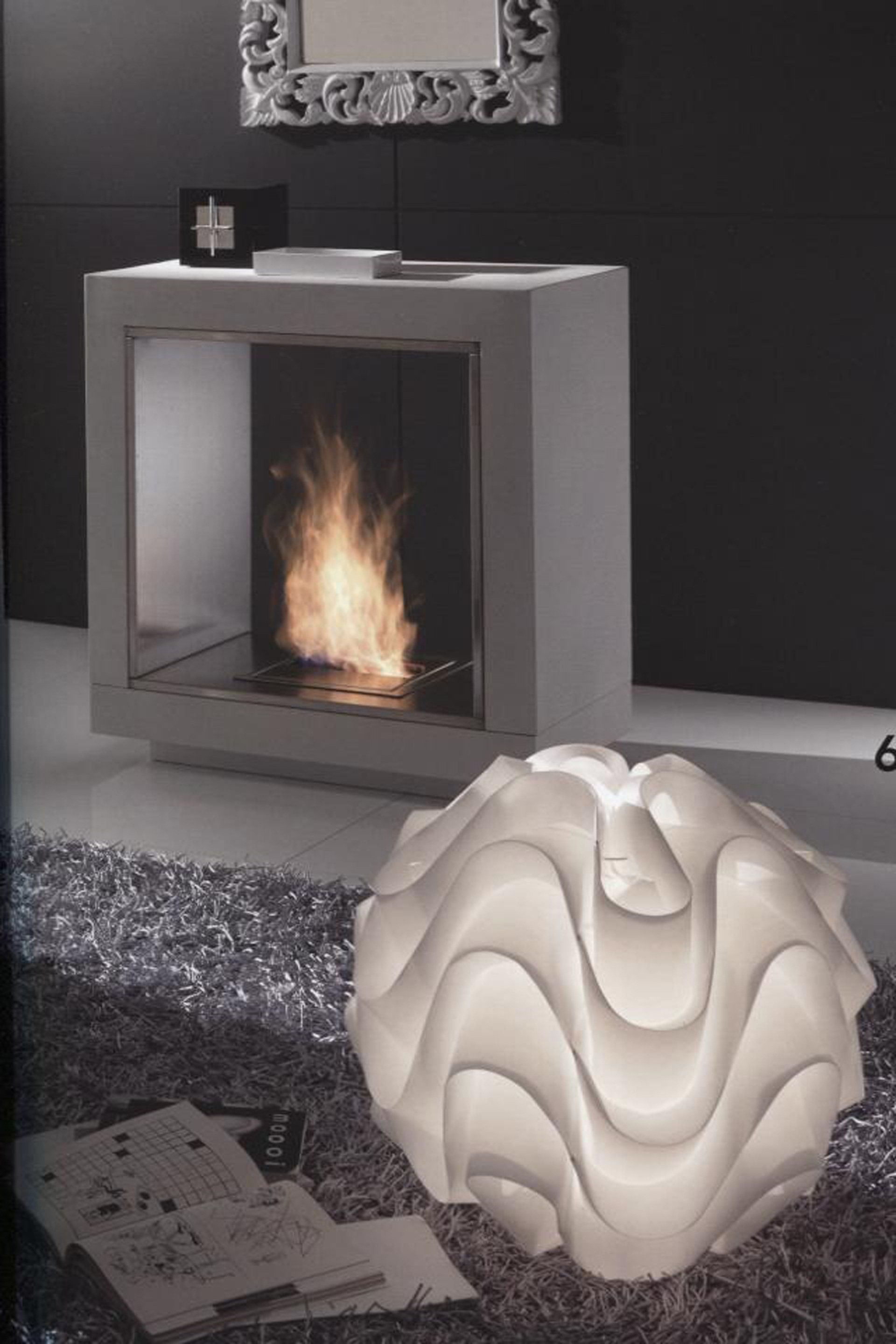 Camino moderno con fiamme, lampada bianca accesa e tappeto grigio a pelo lungo.