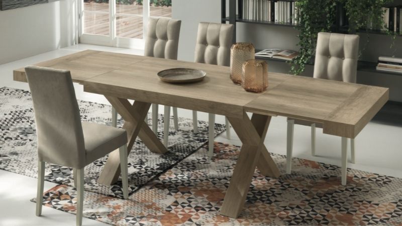 Tavolo da pranzo in legno con sedie su un tappeto fantasia, vasi decorativi sul tavolo.