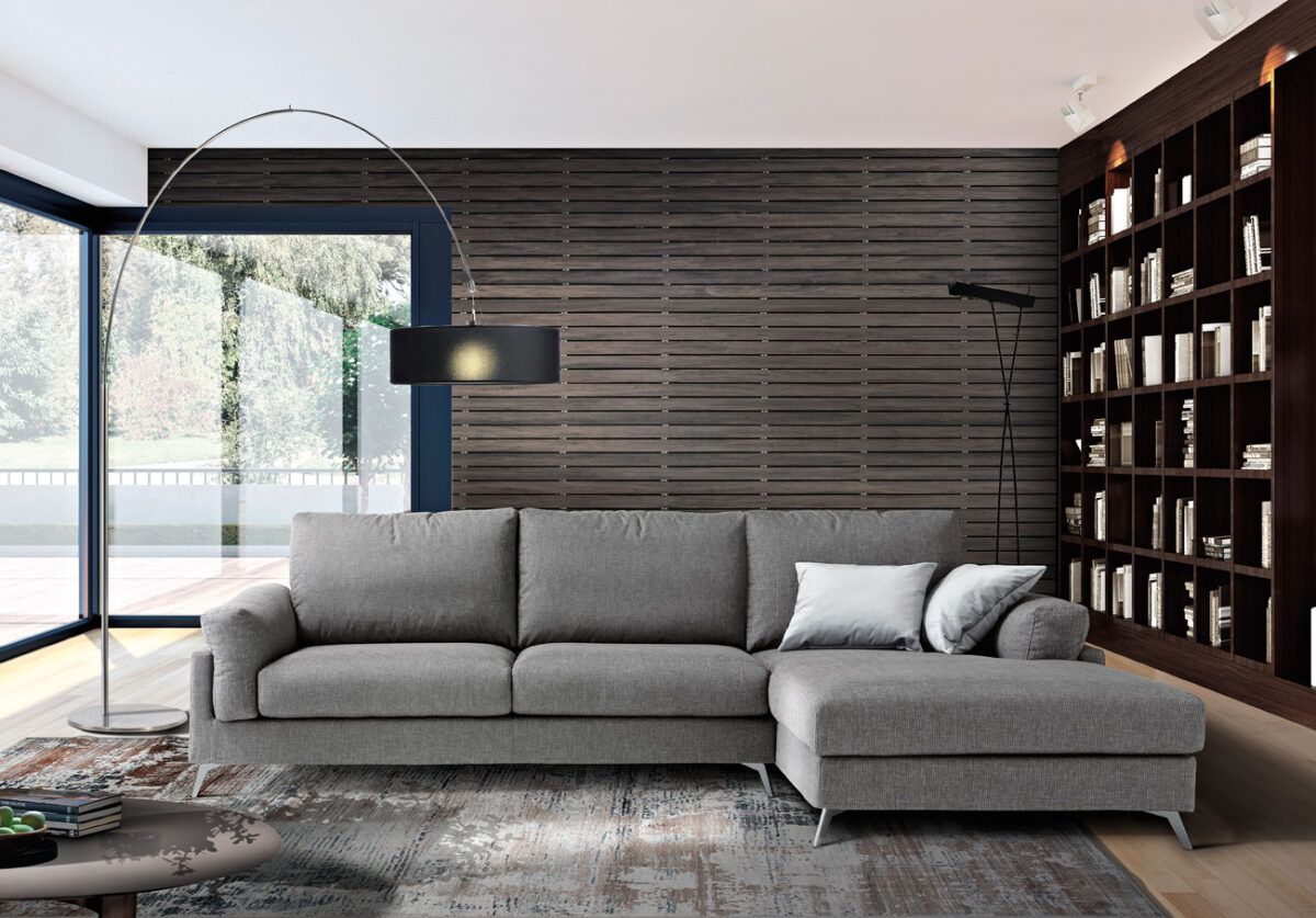 Divano componibile grigio in un soggiorno moderno con una grande finestra e una libreria integrata.