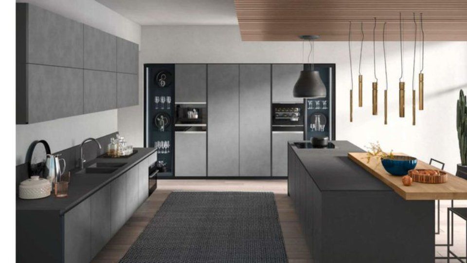 Moderna cucina grigia con isola, mobili, elettrodomestici e lampada a sospensione.
