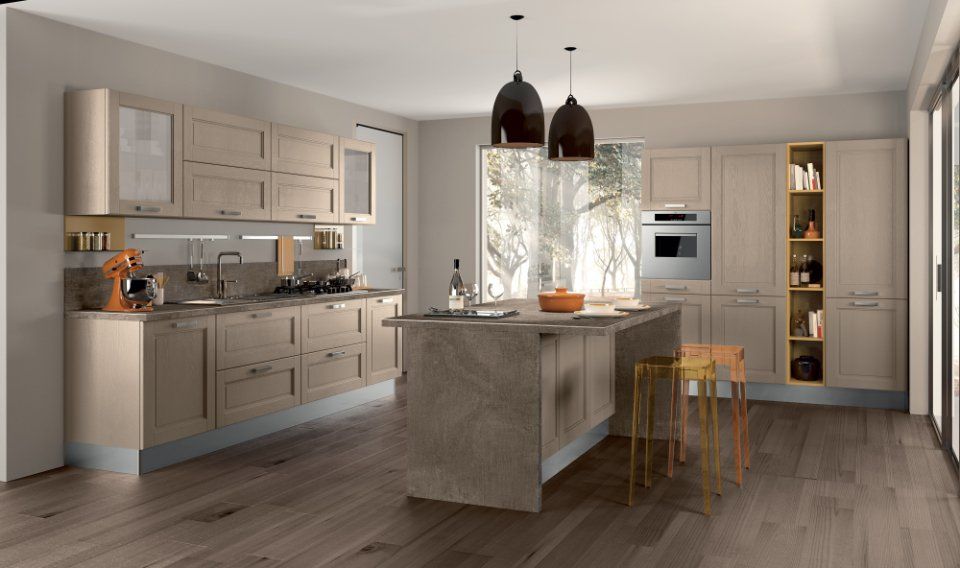 Cucina moderna con mobili in legno chiaro, isola e luci sospese.