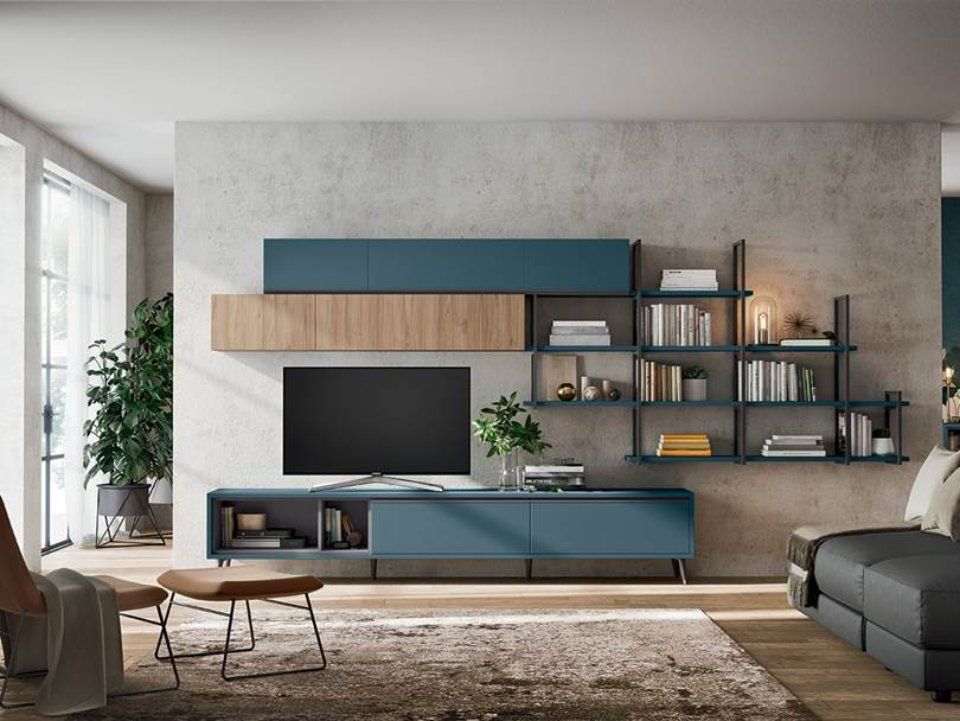 Soggiorno moderno con parete attrezzata nei toni del blu e del legno, TV, scaffali e divano grigio.