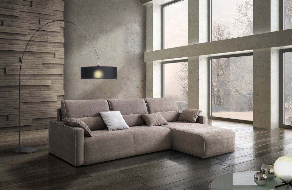 Divano componibile beige in un soggiorno moderno con ampie finestre, pavimento in legno e lampada da terra.