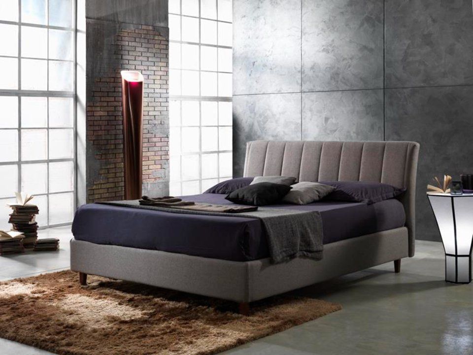 Camera da letto moderna con letto imbottito, tappeto, finestre alte e illuminazione decorativa.