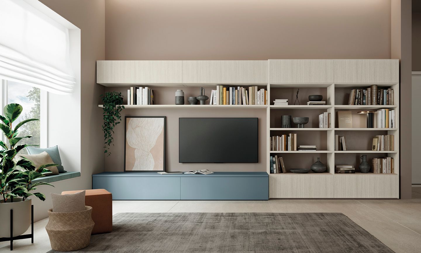 Soggiorno con mobile TV a parete. Mobili blu e in legno, scaffali con libri, piante, TV, finestra, tappeto.