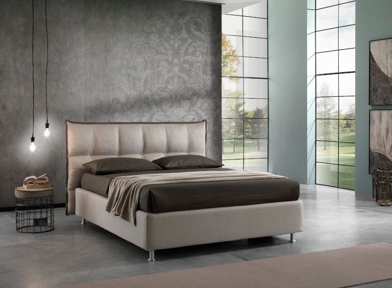 Una camera da letto moderna con un letto imbottito beige, pareti grigie e grandi finestre che si affacciano su un paesaggio verde.