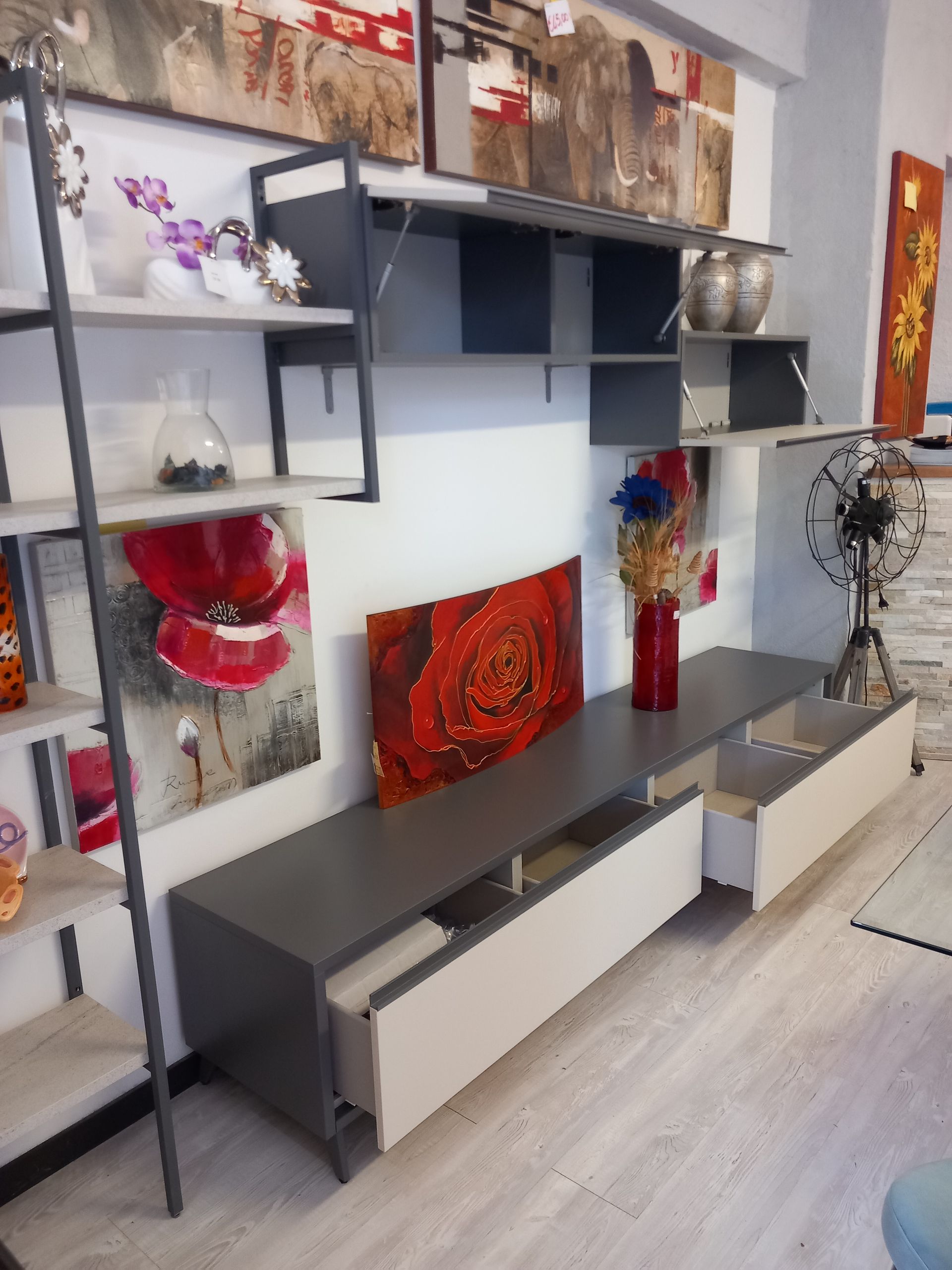Moderna parete attrezzata grigia e bianca con ripiani aperti, cassetti e opere d'arte.