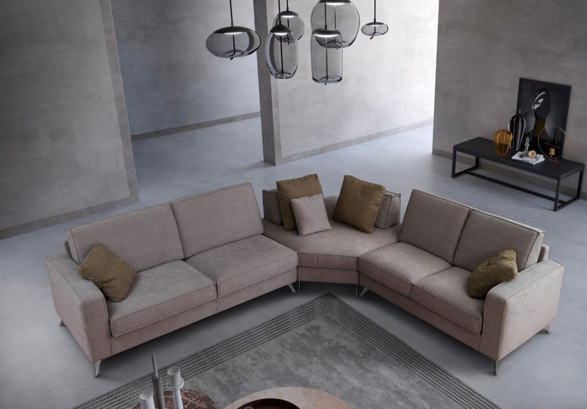 Divano componibile beige in un soggiorno moderno con tappeto e illuminazione dall'alto.