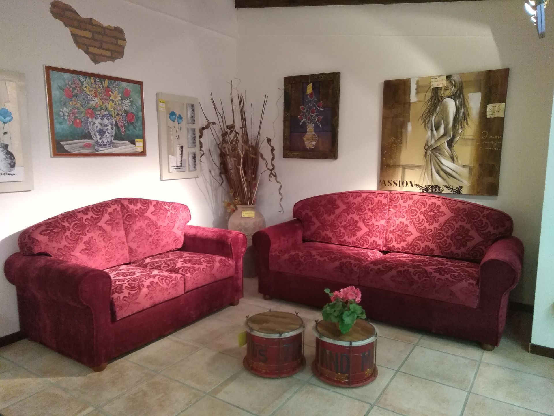 Soggiorno con divani rossi, quadri e oggetti decorativi.