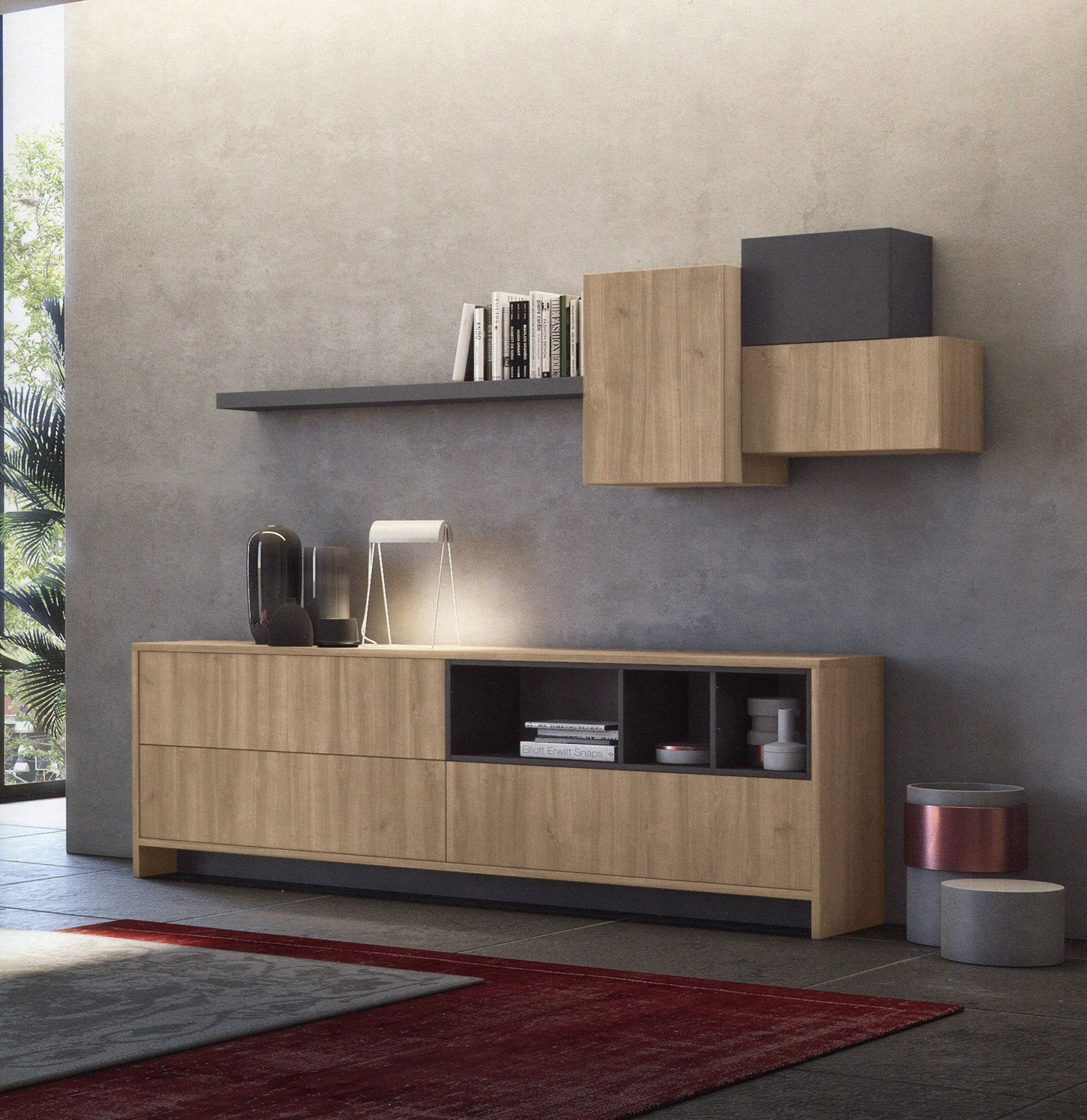 Credenza in legno e scaffale contro una parete grigia, libri, lampada e tappeto rosso.