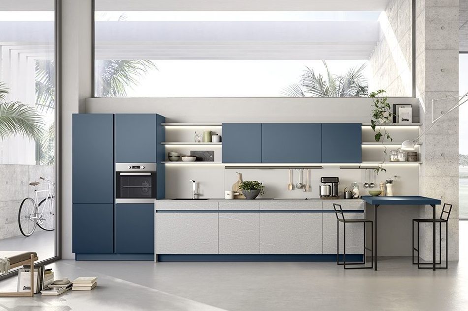 Moderna cucina blu e grigia con ampia finestra, dotata di elettrodomestici da incasso e bancone per la colazione.