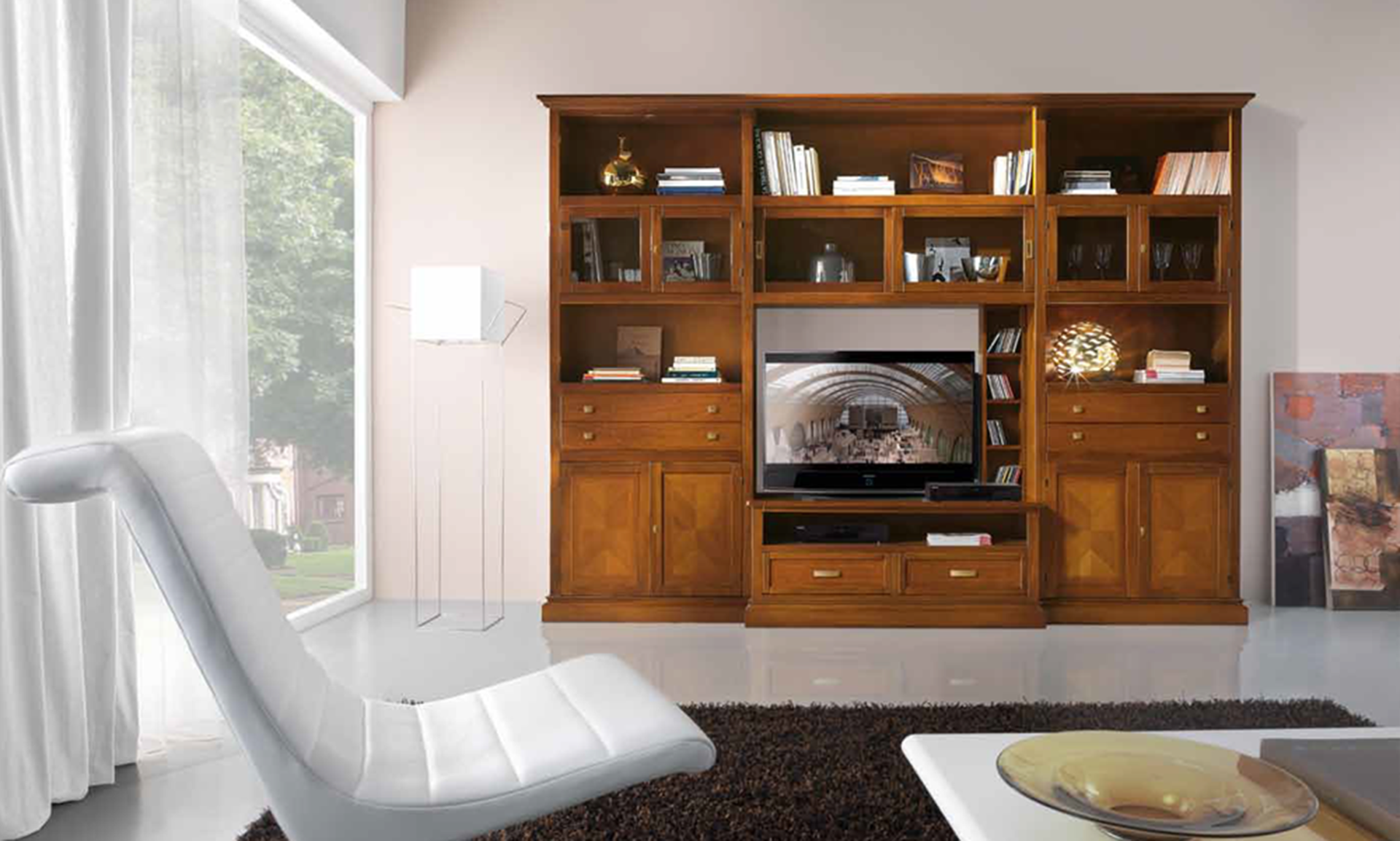 Centro multimediale in legno con TV, libri e oggetti decorativi in un soggiorno; una sedia bianca e una finestra.