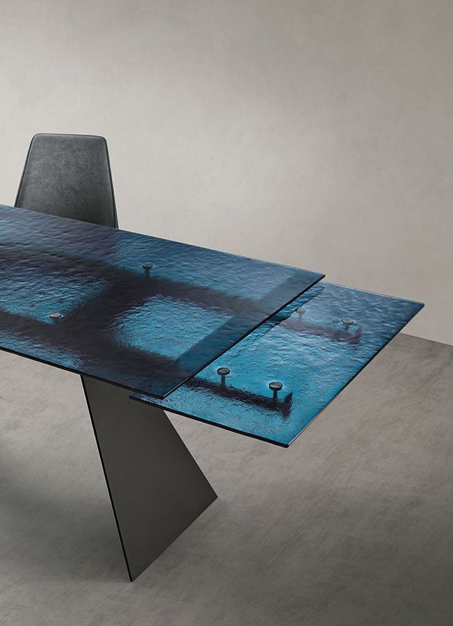 Tavolo da pranzo moderno in vetro blu con motivo a trama acquatica, gamba grigia e sedia grigia.