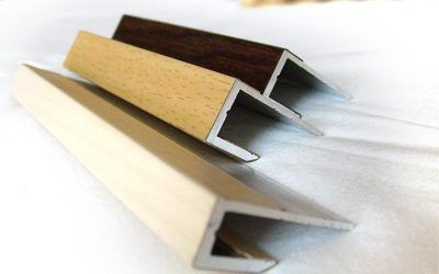 Tre elementi decorativi a forma di L: crema, legno chiaro e marrone scuro, angolati.