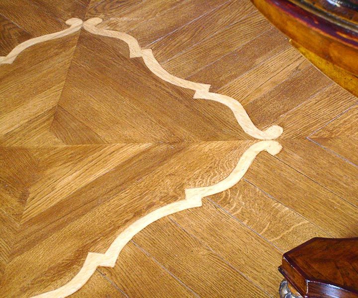 Pavimento in parquet con intarsi in legno chiaro.