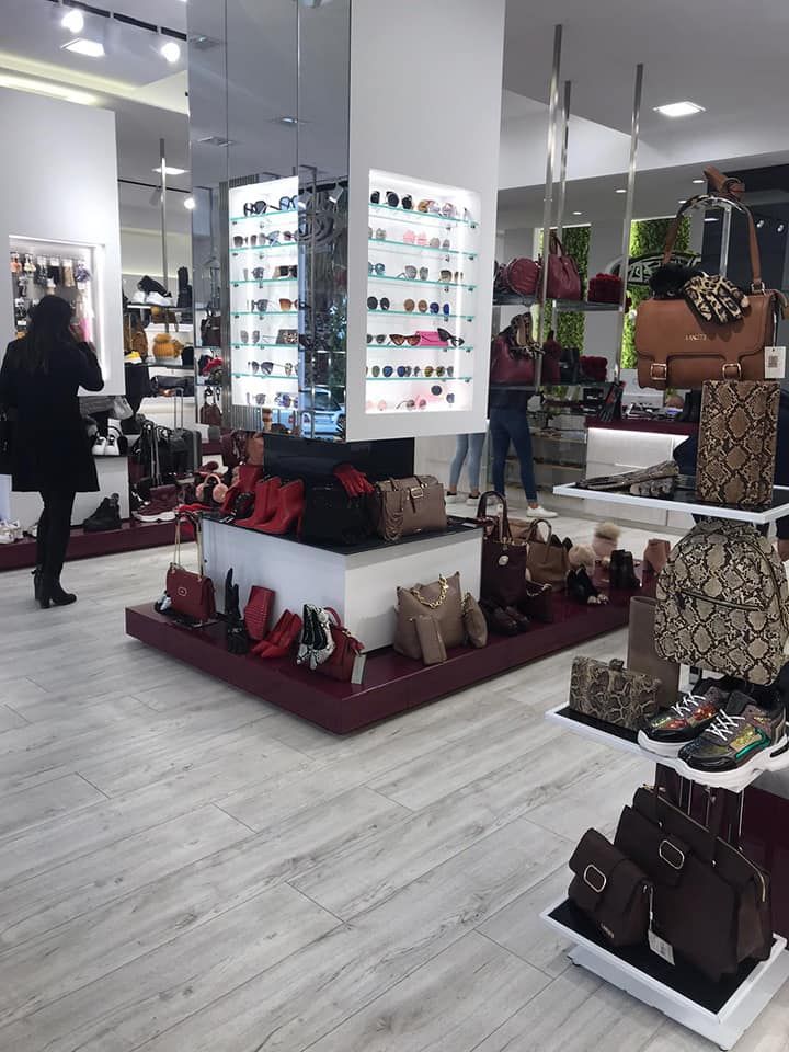 Interno di un negozio di scarpe e borse. Espositori di scarpe, borse e accessori. I clienti curiosano.