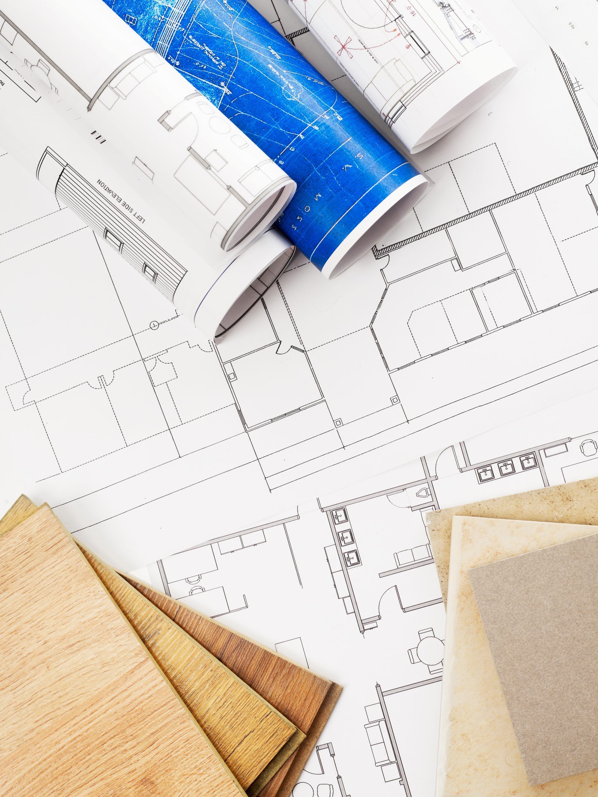 Progetti, campioni di tessuto e progetti arrotolati su un tavolo, probabilmente destinati alla progettazione di interni o alla costruzione.