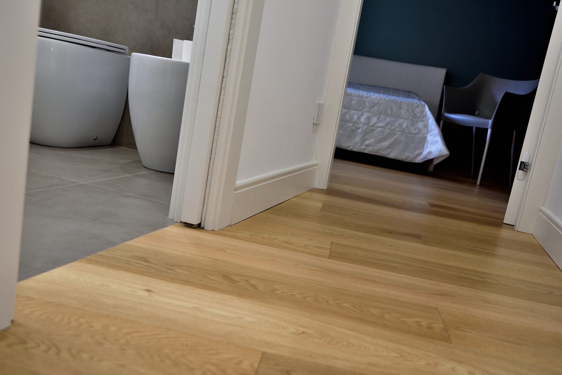 Il pavimento in legno conduce a una porta con un bagno e una camera da letto visibili.