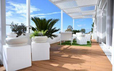 Terrazza esterna con mobili bianchi, piante e cielo azzurro.