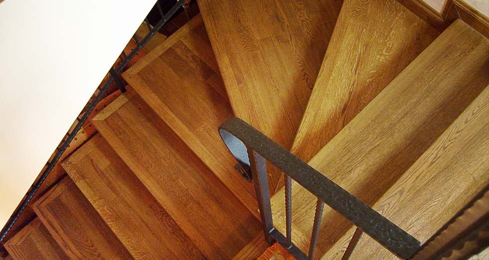 Scala a chiocciola in legno con corrimano in metallo nero.