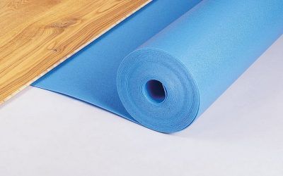 Rotolo di materassino blu accanto al pavimento in legno.
