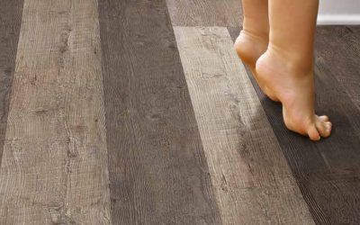 Piedi nudi su un pavimento effetto legno. Un piede è sollevato.