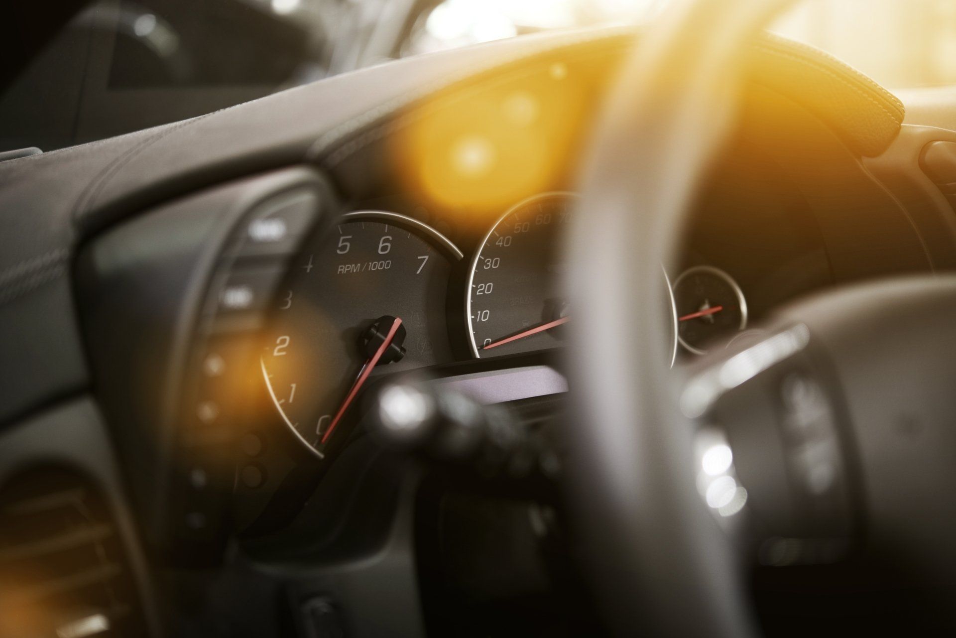 A close up of a car dashboard with a speedometer and a steering wheel.
