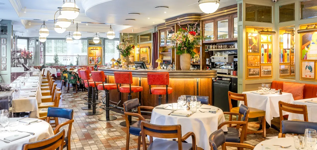 Vibrant restaraunt interior with a crescent bar and numerous cloth-covered tables