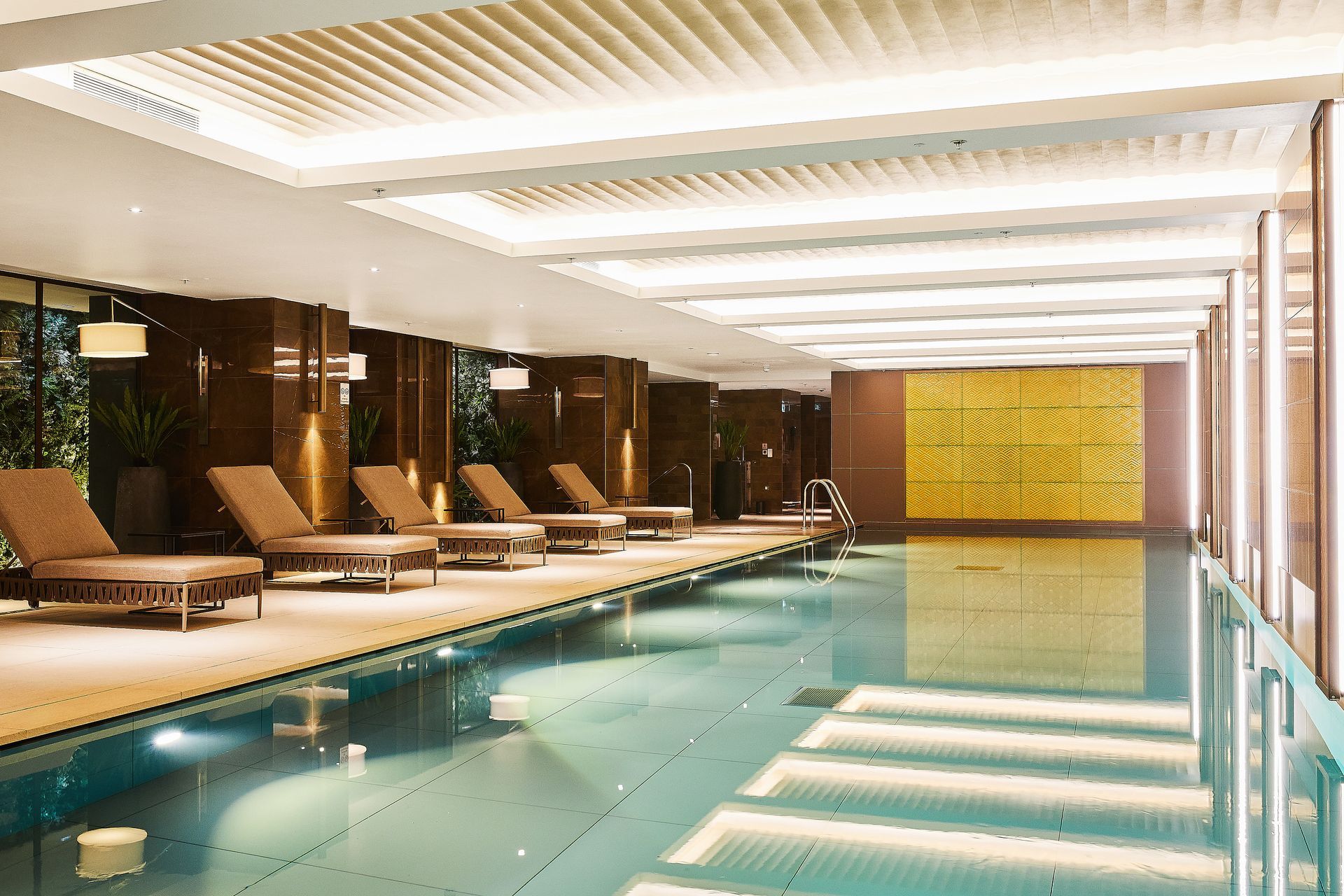 Indoor hotel spa pool with lounge chairs and warm lighting