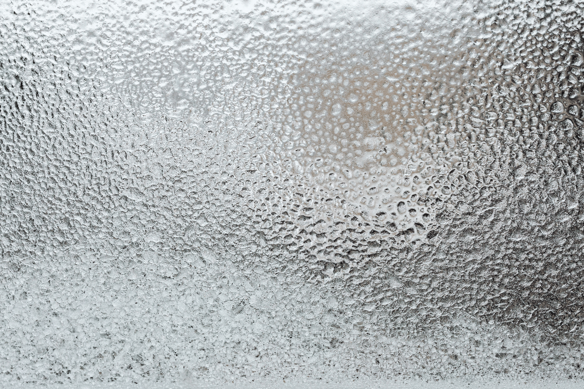 Close-up of condensation on glass, creating a textured, blurry gray and white surface.