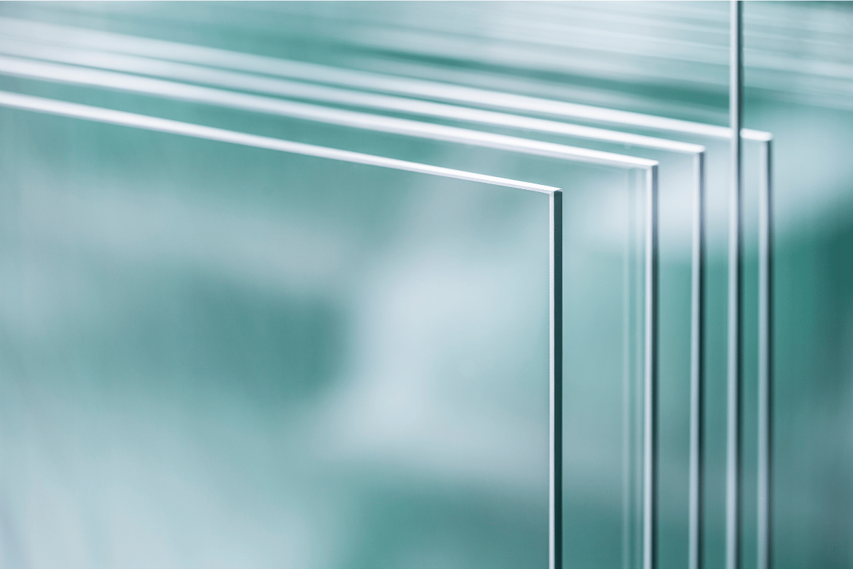 Stacks of clear glass sheets, edges visible, indoors.