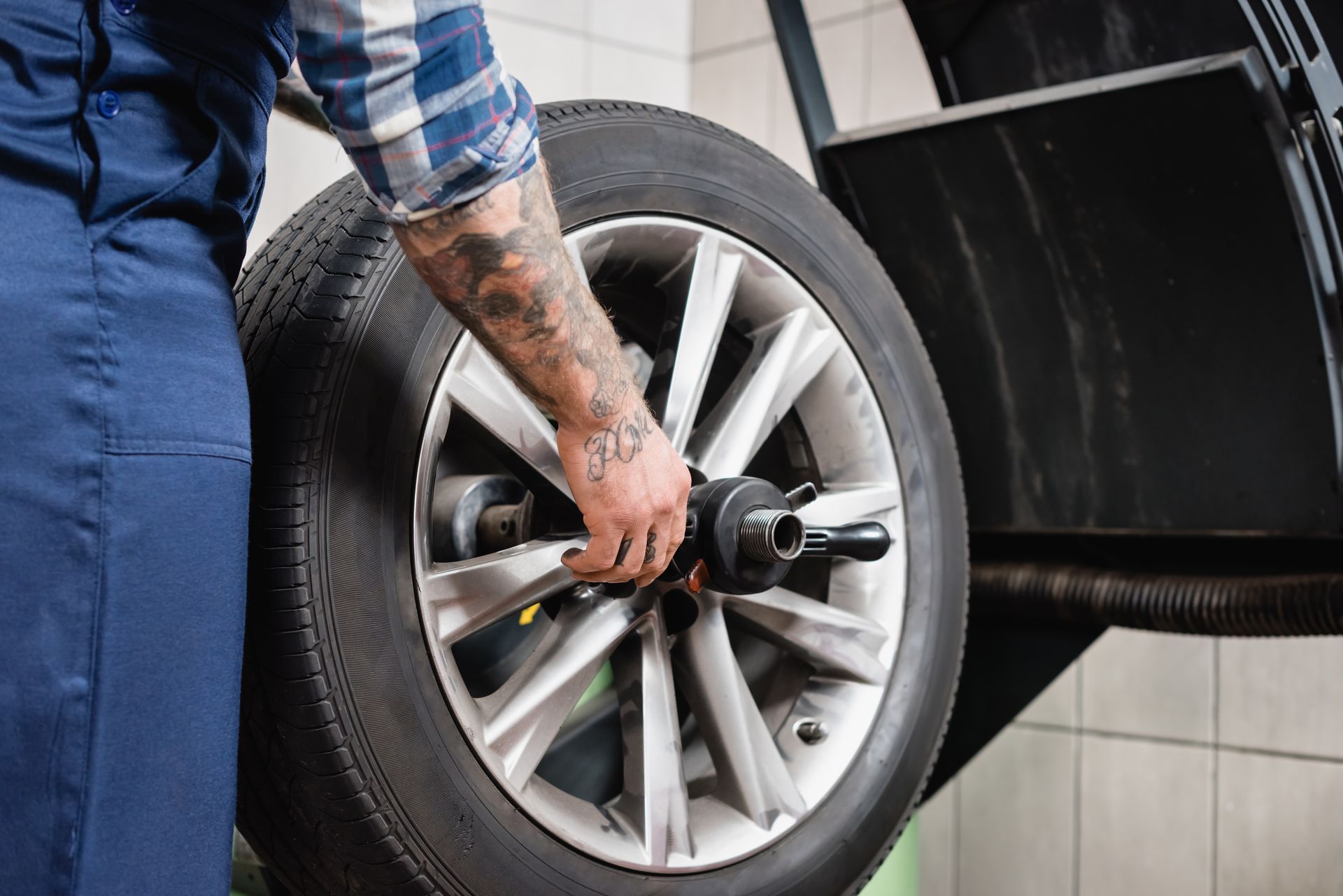 Mechanic balancing a car tire on a machine, checking alignment in a garage.