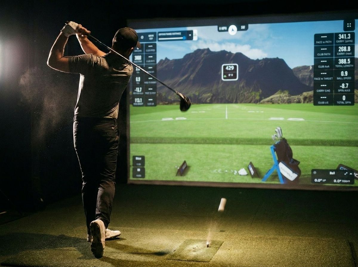 Golfer swinging indoors at a virtual driving range with a large projected golf simulator screen