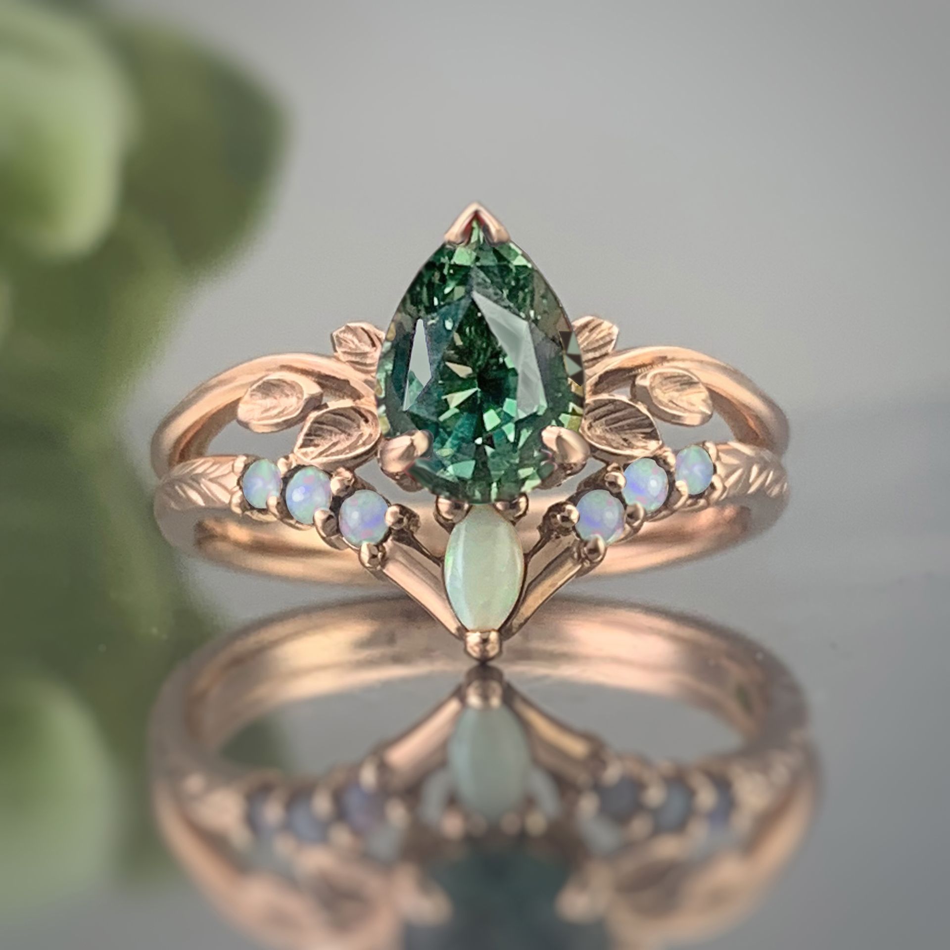 A pear shaped green sapphire and opal ring is sitting on a table.